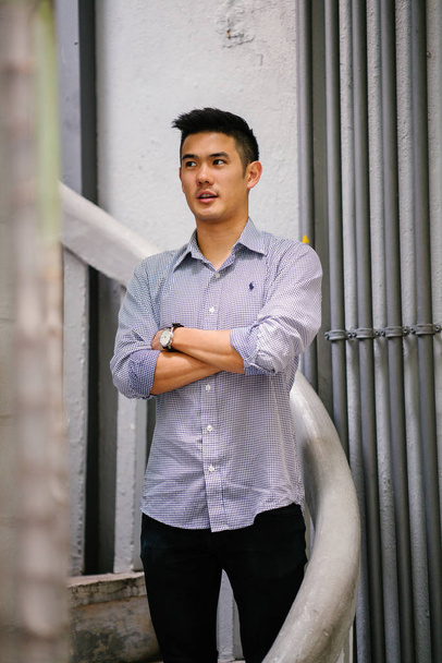 Portrét pohledný, mladá, inteligentní Čínská Asijská muž v obleku, s úsměvem a stojící v den. Má krátké vlasy a na sobě šedý oblek. - Fotografie, Obrázek