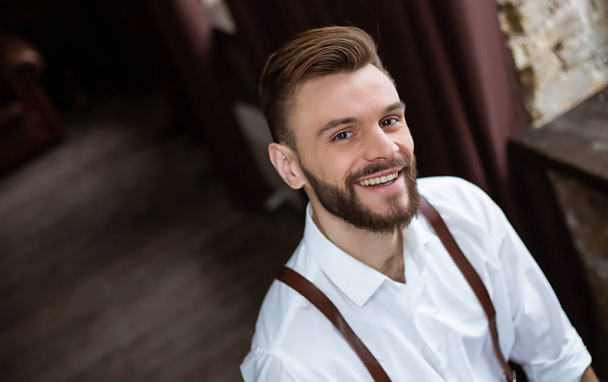 Щасливий портрет усміхненого красивого бородатого чоловіка в білій сорочці з дуже гарним настроєм
. - Фото, зображення