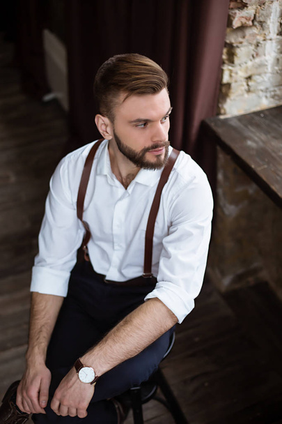 Fashion stylish confident portrair of handsome bearded guy on the big window looking away - Foto, Imagen