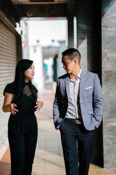 portrait of two professional business people walking and talking. They are deep in conversation as they walk on a street in a city in Asia. The man and woman are both professionally dressed. - Fotografie, Obrázek
