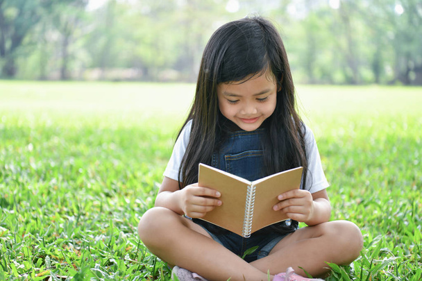 Koncepcje edukacji. Dziewczyna jest z książką w ogrodzie. Być - Zdjęcie, obraz