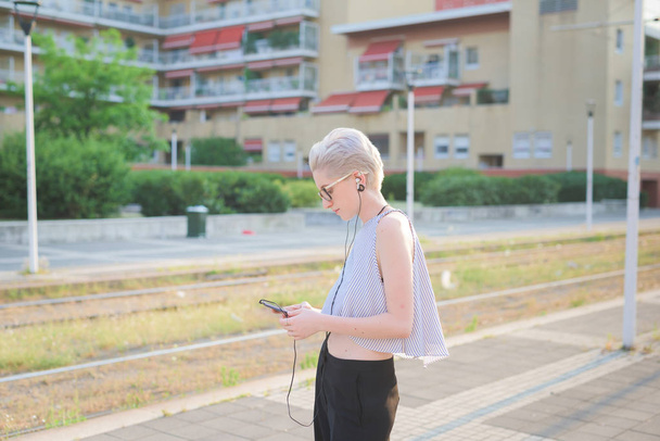 jovem mulher ouvir música segurando smartphone na cidade
  - Foto, Imagem
