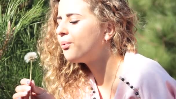 piękna dziewczyna w kręconych włosów portret dmuchanie lato mniszek - Materiał filmowy, wideo