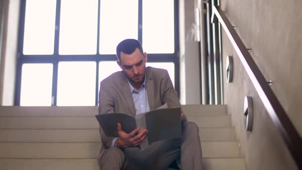 Geschäftsmann mit Ordner sitzt auf Treppe - Filmmaterial, Video