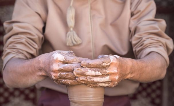 manos de un hombre omaní haciendo un pedazo de cerámica
 - Foto, Imagen