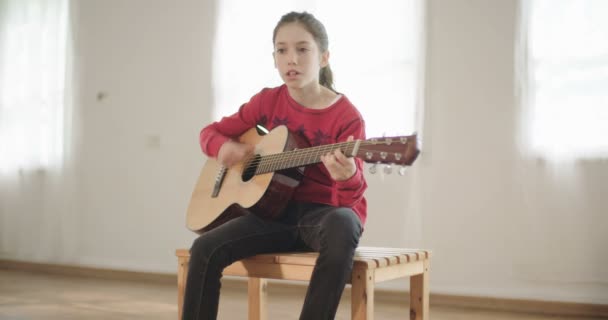 νεαρό κορίτσι παίζει κιθάρα και το τραγούδι - Πλάνα, βίντεο