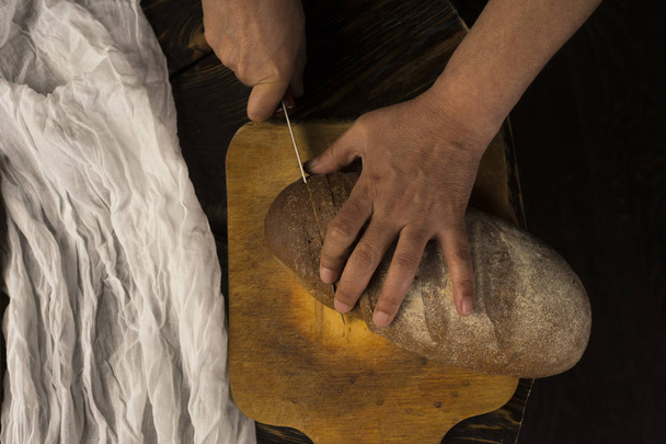 Концептуальная художественная фотография пожилой женщины руки режут хлеб с
 - Фото, изображение