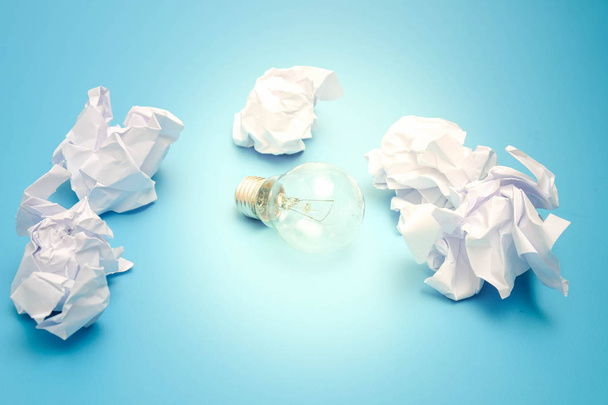 great concept with crumpled office paper and light bulb on a blue background - Photo, Image