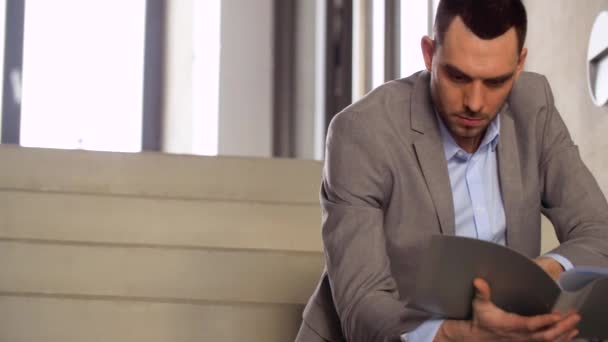 businessman with folder sitting on stairs - Кадри, відео