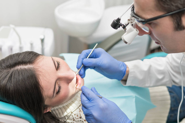 Zubař v speciální brýle zkoumá pacienta - Fotografie, Obrázek