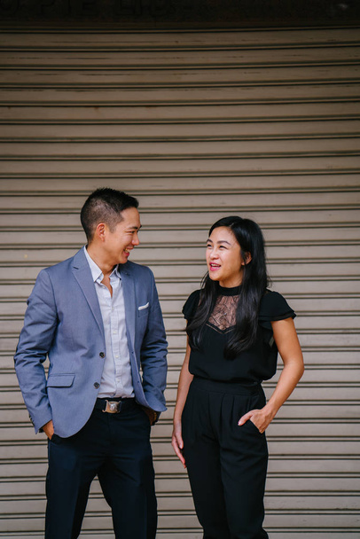 portrait of two professional business people walking and talking. They are deep in conversation as they walk on a street in a city in Asia. The man and woman are both professionally dressed. - Foto, Imagen
