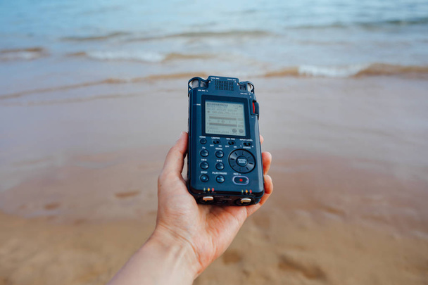 portable audio recorder in hand recording ambient sounds of sea - Photo, Image