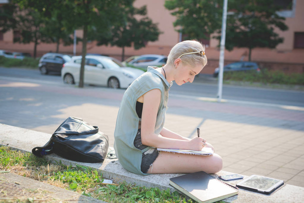 Молодая женщина на открытом воздухе сидя записывает на повестке дня
 - Фото, изображение