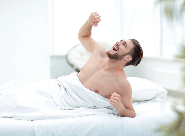 smiling man waking up in a cosy bedroom - Photo, Image