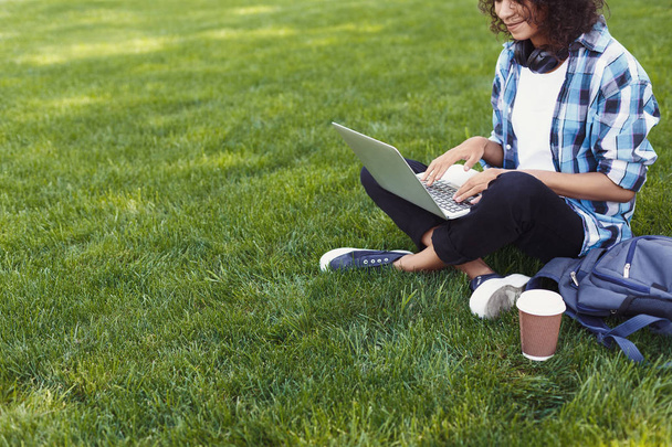 Неузнаваемая чёрная женщина использует ноутбук в парке
 - Фото, изображение