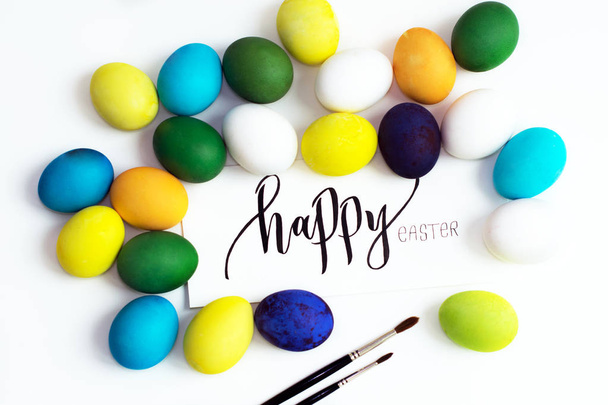 Oeufs colorés festifs de Pâques sur fond blanc avec une calligraphie de carte de vœux "Joyeuse Pâques". œufs jaune, bleu, vert et bleu, orange et violet
 - Photo, image