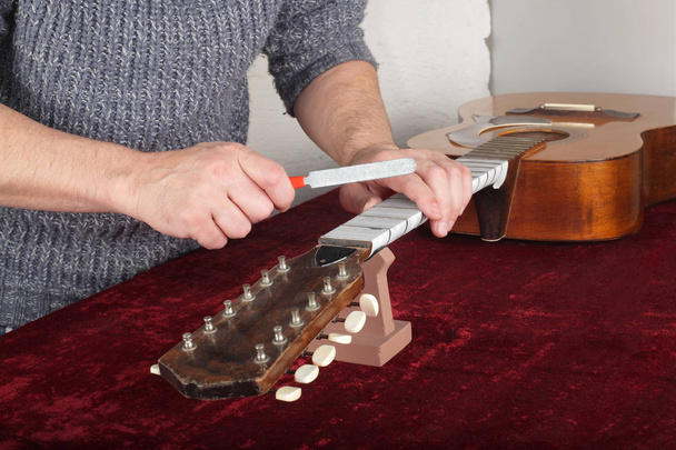Reparatur und Service der Gitarre - Arbeiter zum Schärfen des Spezialwerkzeugs - Foto, Bild