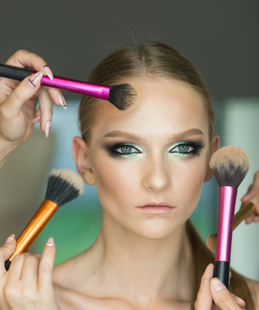 Hands apply makeup on model face. Woman getting powder on skin with brushes, makeup. Woman with young face in beauty salon. Visage course, professional make up. Girl with healthy skin, skincare - Valokuva, kuva