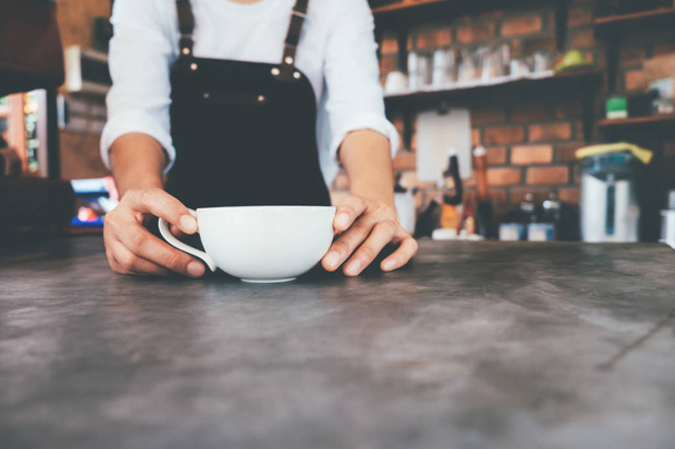 Bir fincan kahve tutan Closeup barista el. - Fotoğraf, Görsel