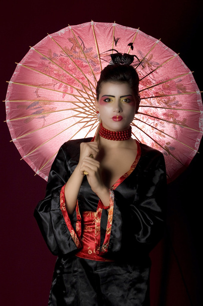 Sexy young geisha holding a painted umbr - Foto, Bild