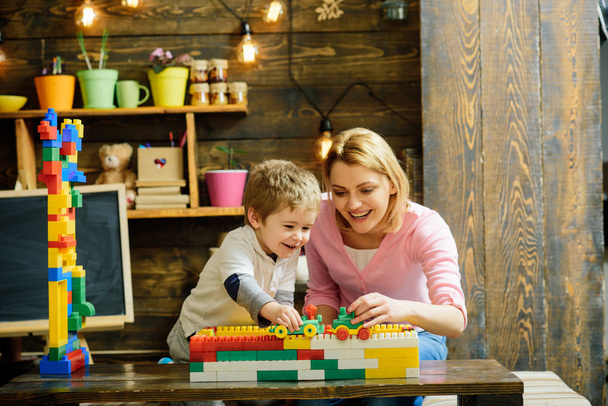 Mother with child playing with car toys and plastic blocks at home. Childhood and family games concept. - Photo, Image