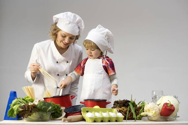 Mom and kid with smiling face cooking spaghetti together. - Foto, immagini