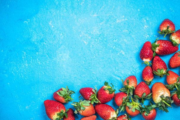 Mercado de morangos maduros frescos em fundo vibrante azul
 - Foto, Imagem