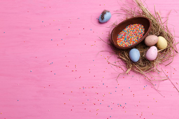 Chocolate Easter eggs, quail eggs and colorful candies on a bright pink background. Easter sweets concept. - Zdjęcie, obraz