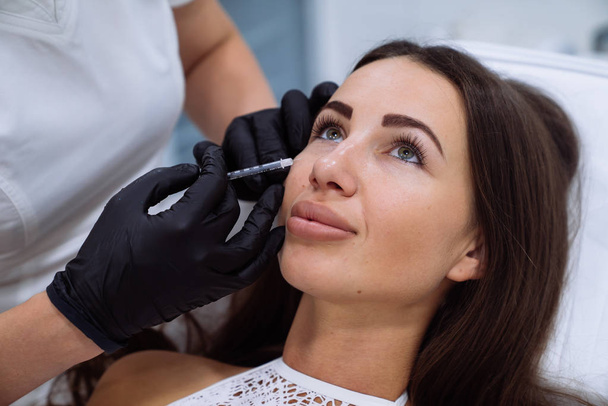 Lähikuva kaunis naisten kasvot ja kosmetologit kädet ruiskulla aikana kasvojen kauneus injektioita. Nuorentaminen ja nesteytys. Kosmetologian käsite
 - Valokuva, kuva