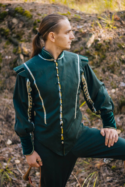 Um tipo sexy na floresta. Com roupas bonitas e velhas de cor verde. Um medieval. Fantasia
.  - Foto, Imagem