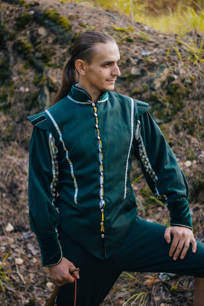 Сексуальна людина в лісі. У красивому, старому одязі зеленого кольору. Середньовічний. Фантазія
.  - Фото, зображення