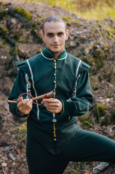 Sexy man in het bos. In mooie, oude kleren van groene kleur. Een middeleeuws. Fantasie.  - Foto, afbeelding