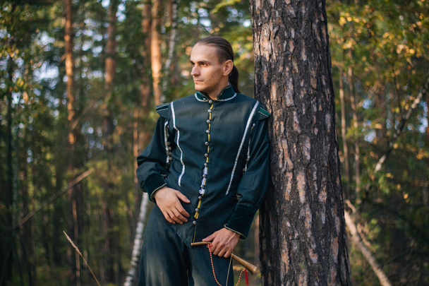 Sexy man in het bos. In mooie, oude kleren van groene kleur. Een middeleeuws. Fantasie.  - Foto, afbeelding