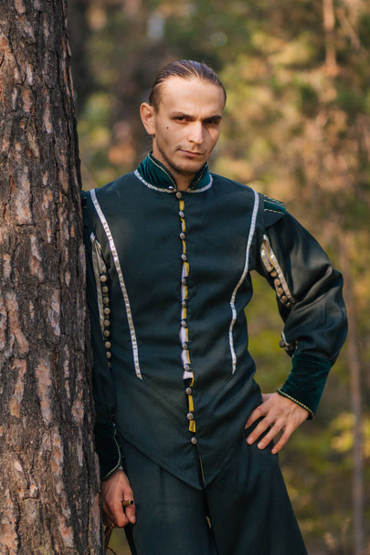 Σέξι άντρα στο δάσος. Στην όμορφη, παλιά ρούχα του πράσινου χρώματος. Ένα μεσαιωνικό. Φαντασία.  - Φωτογραφία, εικόνα
