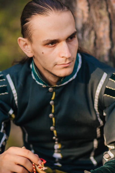 Sexy guy in the woods. In beautiful, old clothes of green color. A medieval . Fantasy.  - Foto, Imagen