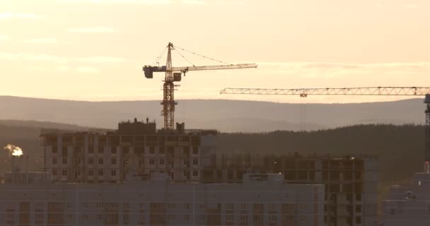 Żuraw wieżowy o budowie przeciwko zachód słońca niebo. Ekaterinburg, Federacja Rosyjska. Wideo. (4k UltraHD) - Materiał filmowy, wideo
