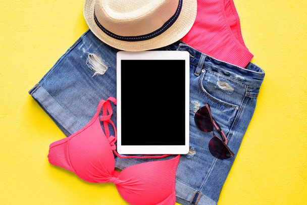Female summer bikini swimsuit and accessories on blue with tablet and sunglasses. - 写真・画像