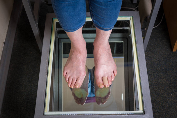 Schritt digitaler Fußscan, Orthesen-Fußscan für maßgeschneiderte Schuheinlagen, Haltungs- und Gleichgewichtsanalyse. Arzt, Patient - Foto, Bild