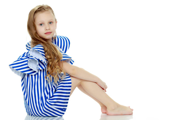 Adorable little blond girl in very short summer striped dress. - Foto, imagen