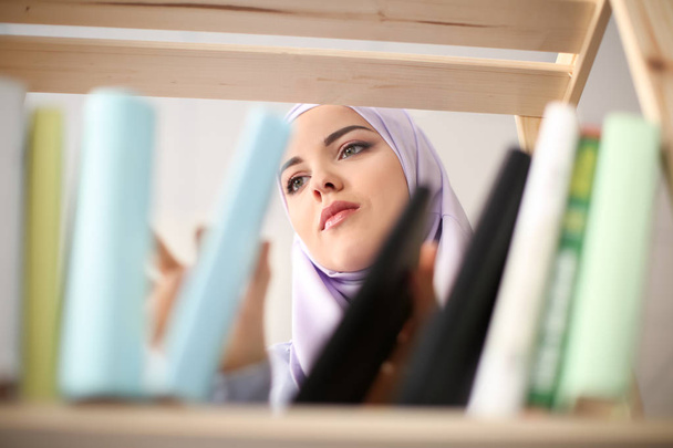Muslim student choosing book from shelf in library - Foto, immagini