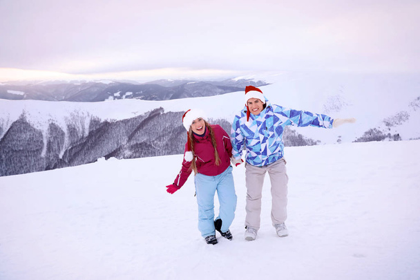 Joyeux couple dans les chapeaux de Père Noël s'amuser à la station enneigée. Vacances d'hiver
 - Photo, image