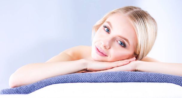 Young woman lying on a massage table,relaxing with eyes closed - Fotografie, Obrázek