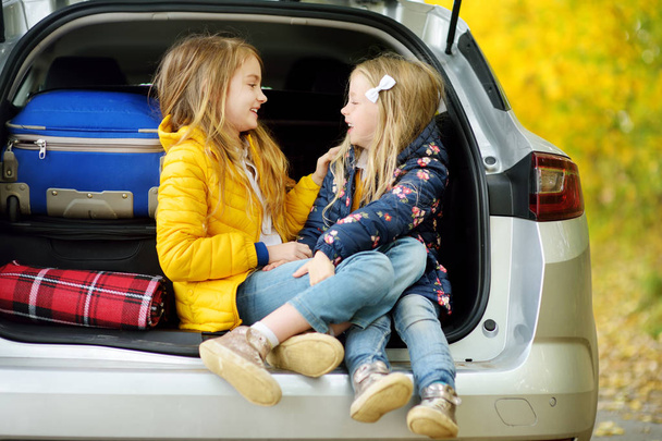 Two happy little sisters having fun sitting in car  - Foto, Bild