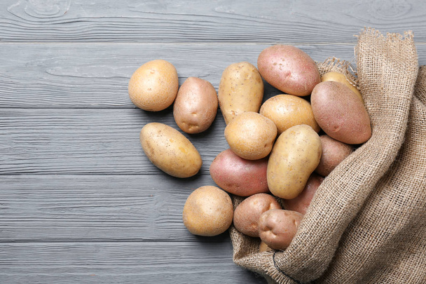 Fresh raw potatoes on wooden table - Valokuva, kuva
