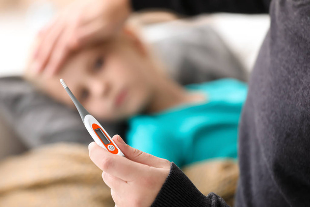 Father measuring temperature of his sick daughter at home - Photo, image