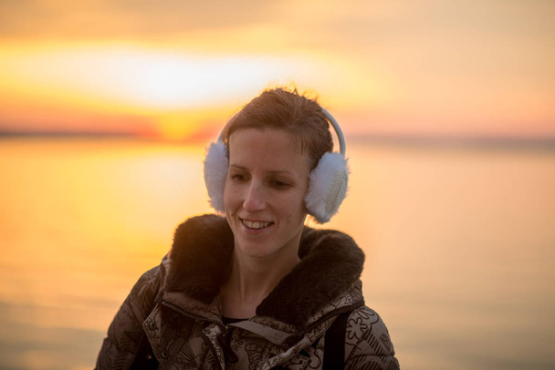 Usmívající se žena nosit chrániče sluchu při západu slunce - Fotografie, Obrázek