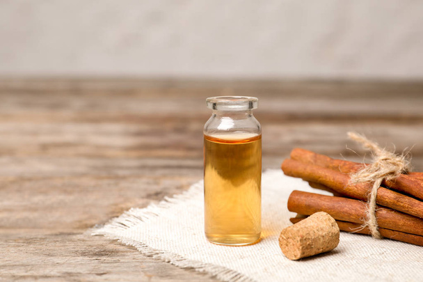Bottle with cinnamon essential oil and sticks on wooden table - Photo, Image