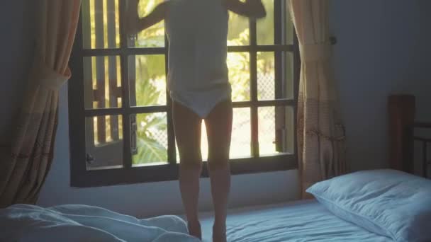 Just awake child girl jumping on the bed at morning in slow motion - Filmati, video