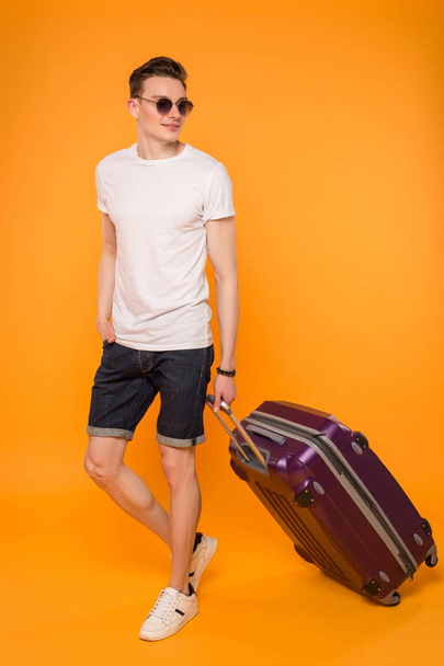 Hauskanpito ja keskittyminen paranemiseen! Trendikäs nuori mies, jolla on lentolaukku, menee hänen kesälomalleen.
. - Valokuva, kuva