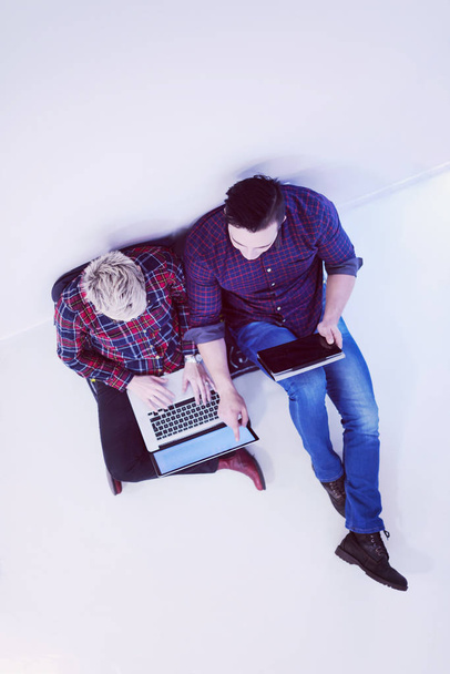 startup business and new mobile technology concept with  young couple in modern bright office interior working on laptop and tablet computer on new creative project and brainstorming, aerial top view - Photo, Image